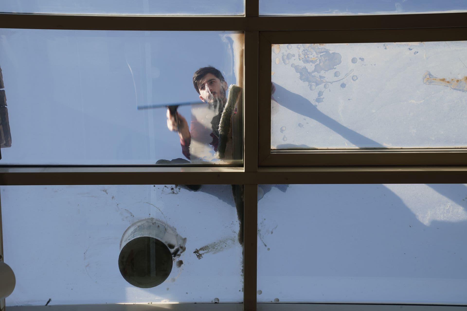 Purified water sheeting dirt away from a glass roof during a reach-and-wash clean